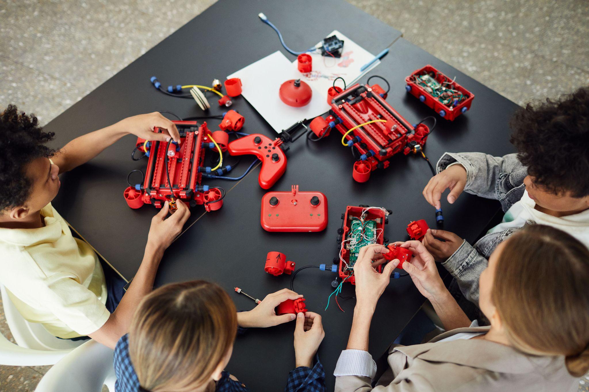 Students and a teacher collaborating on a hands-on robotics build around a workshop table